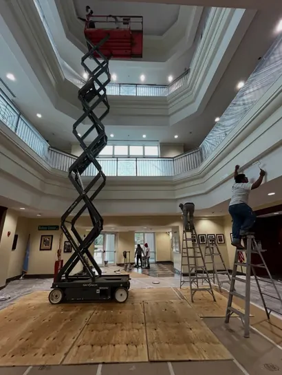 Painter on a scissor lift repainting a commercial atrium